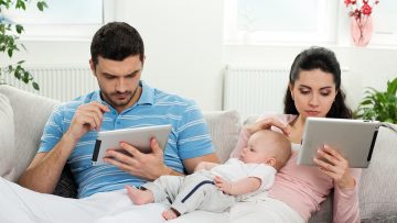 family with baby sitting at home with a tablet PC